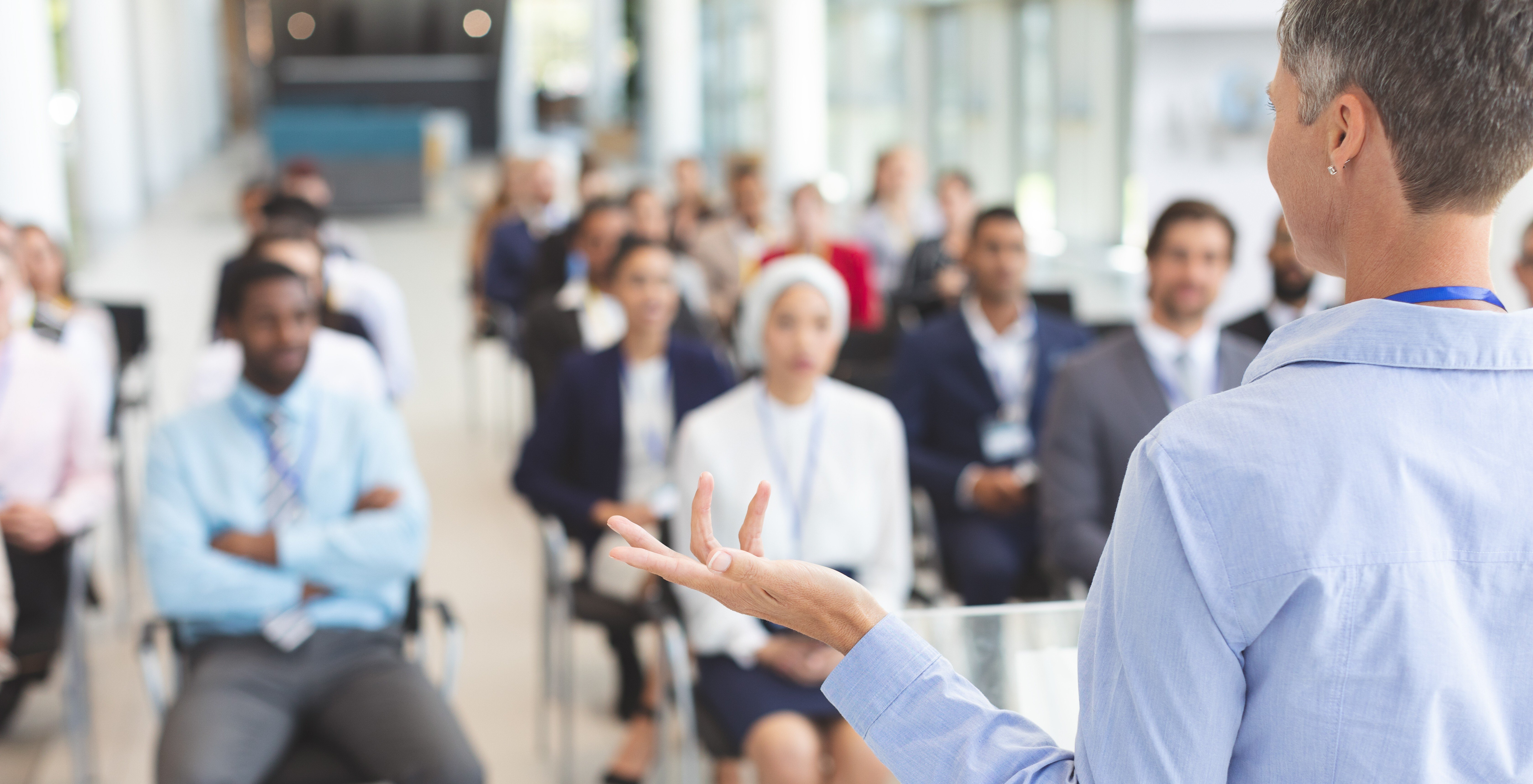 Professional speaker addressing a diverse group of employees during a workplace cyber security training session, emphasizing the importance of human awareness in preventing cyber threats.