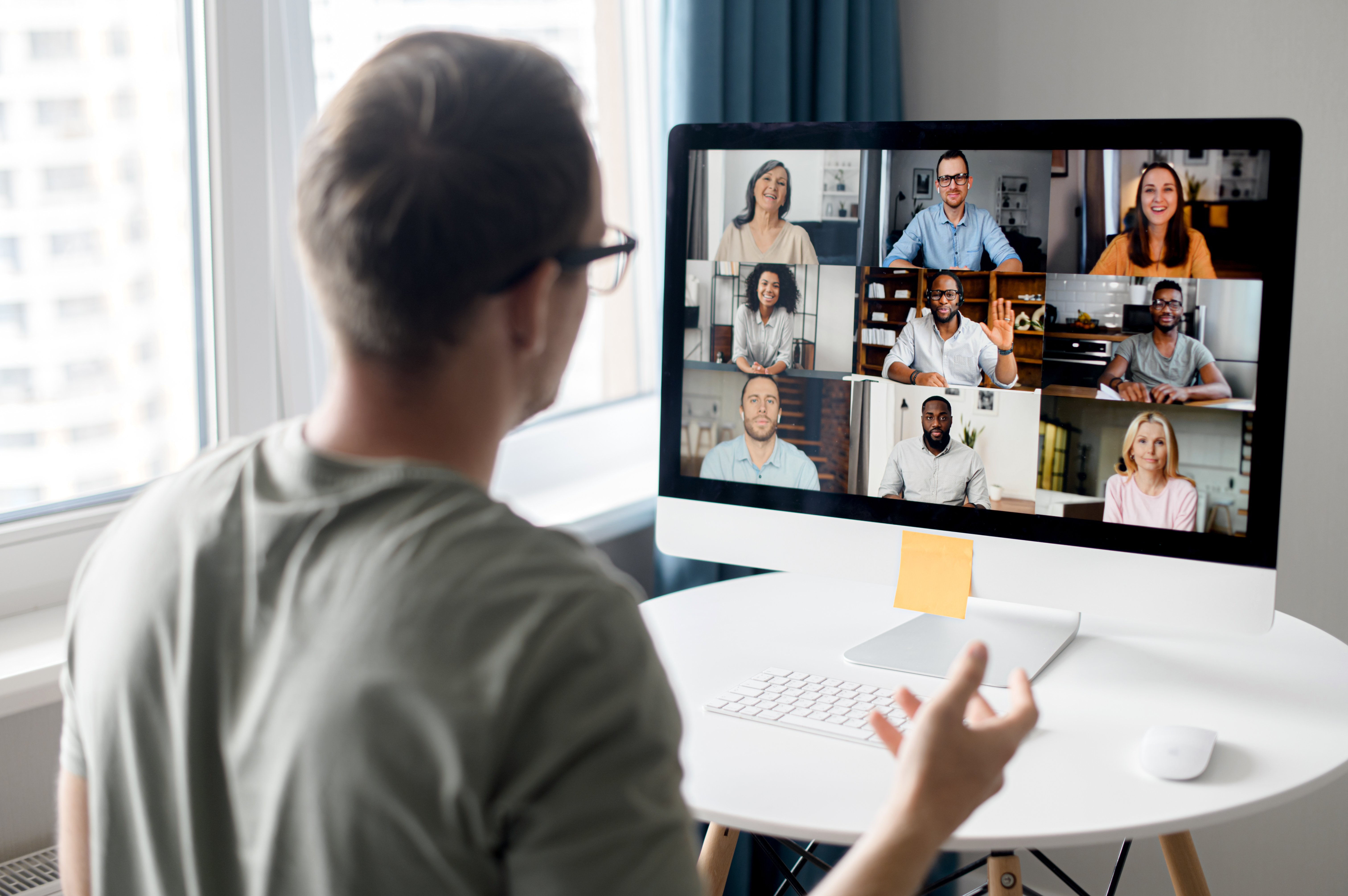 Man on a computer taking a virtual meeting with his colleagues 