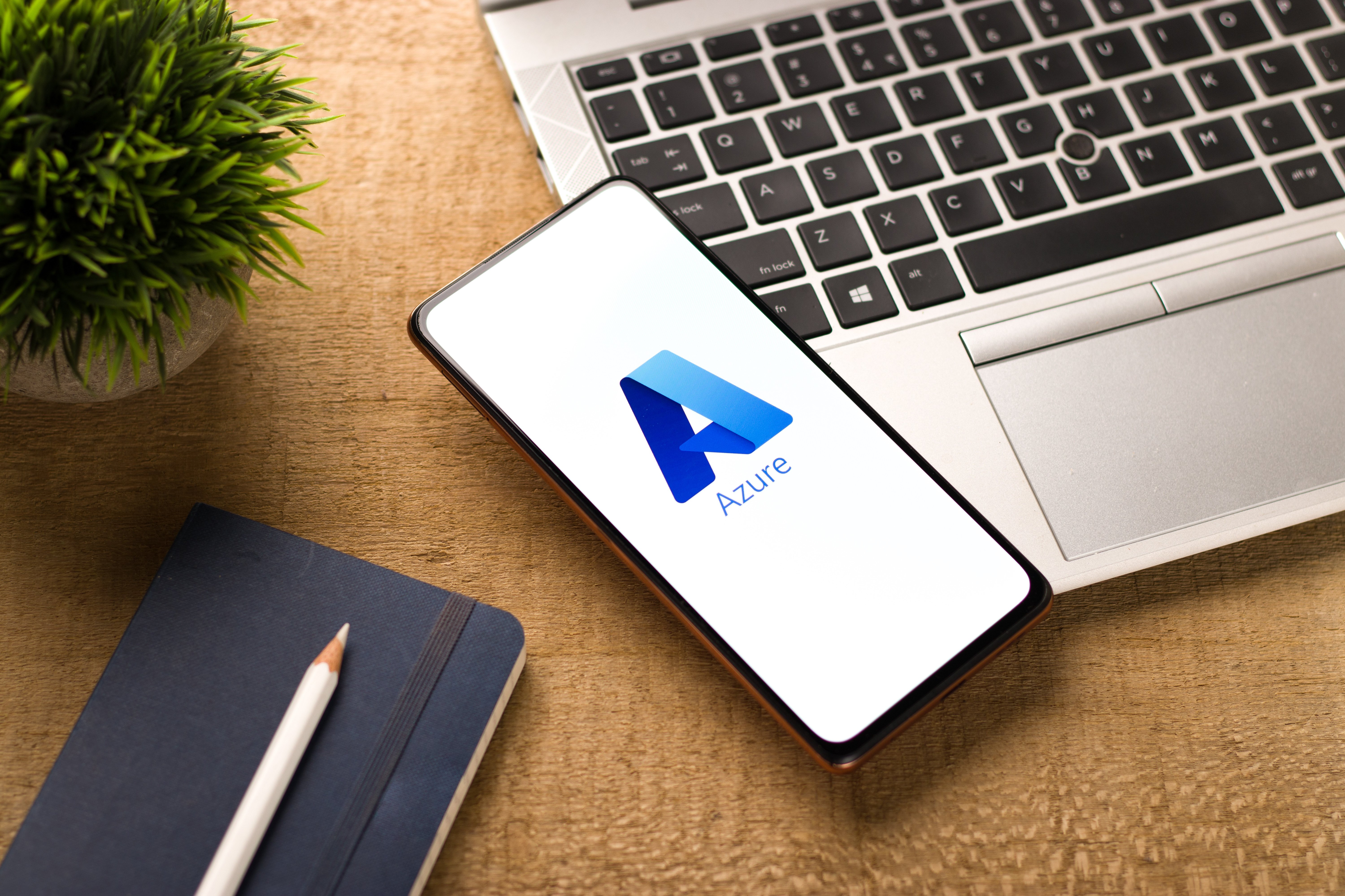 Image of a phone displaying the Microsoft Azure logo, placed on a laptop on a desk.