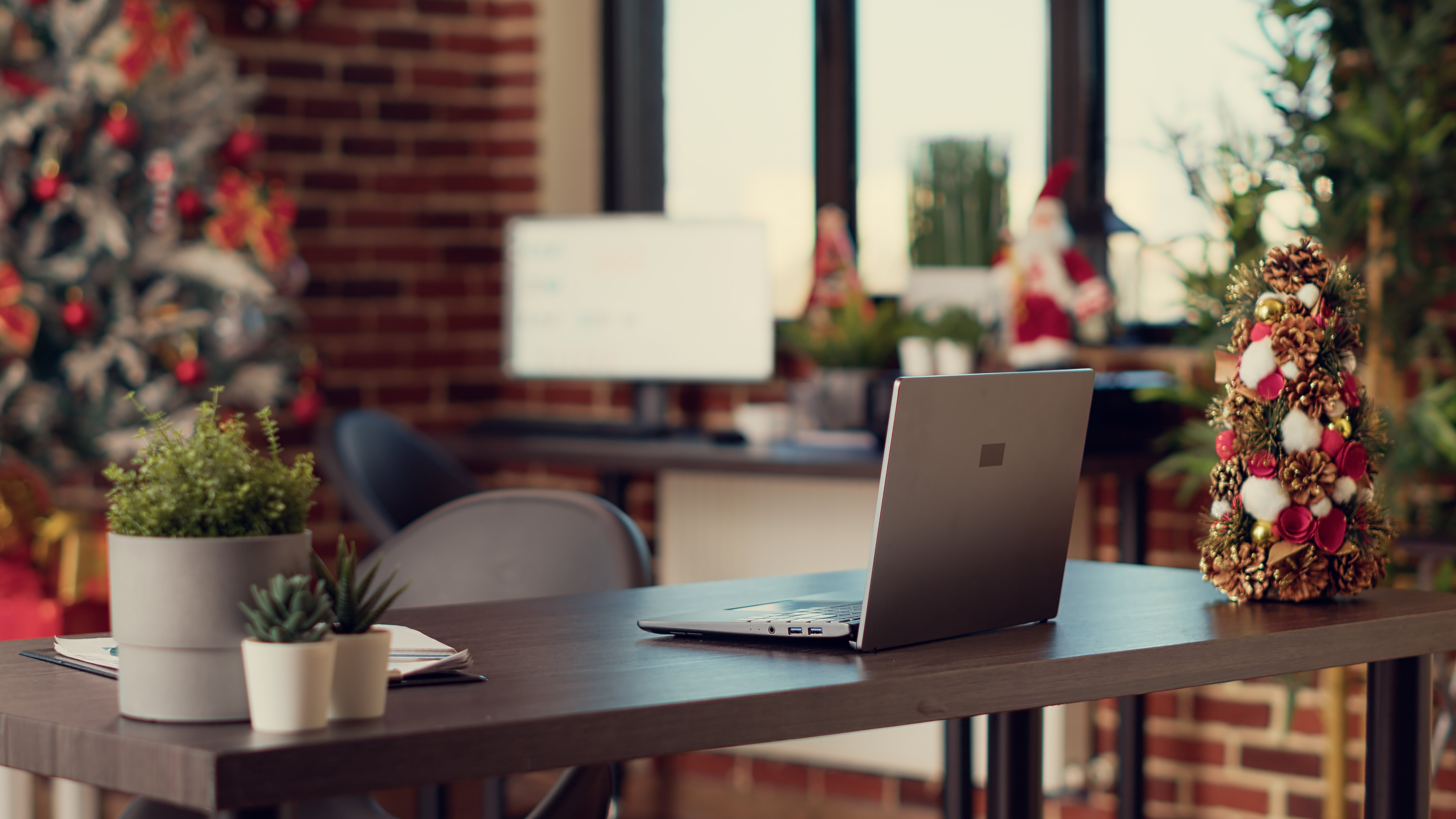 Laptop on wooden desk surrounded by Christmas decorations