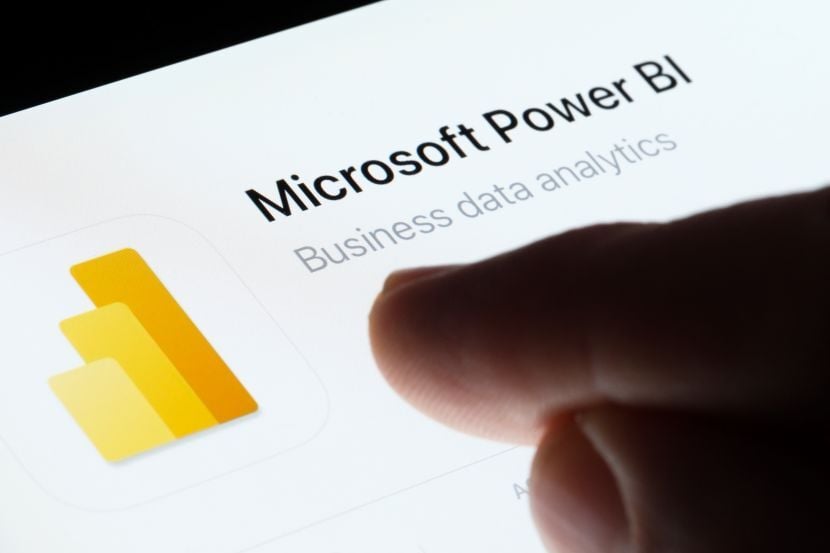 Microsoft Power BI app seen in App Store on the screen of ipad and blurred finger pointing at it. 