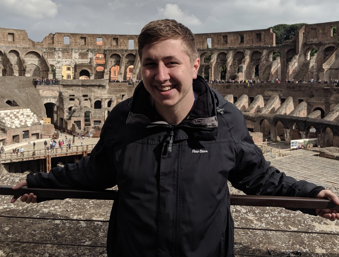 Josh, a Fitzrovia IT employee, stands in front of the Colosseum wearing a black waterproof jacket